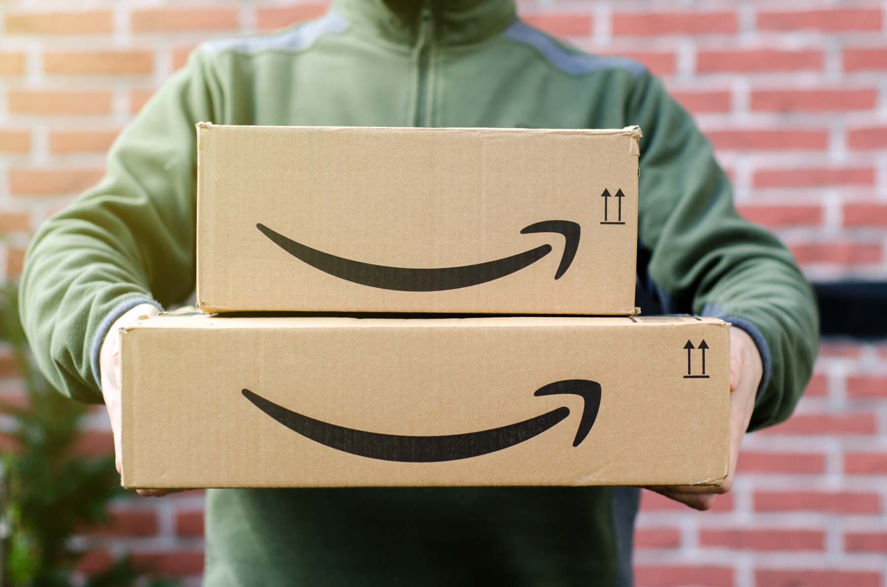 Person hält zwei Amazon-Pakete