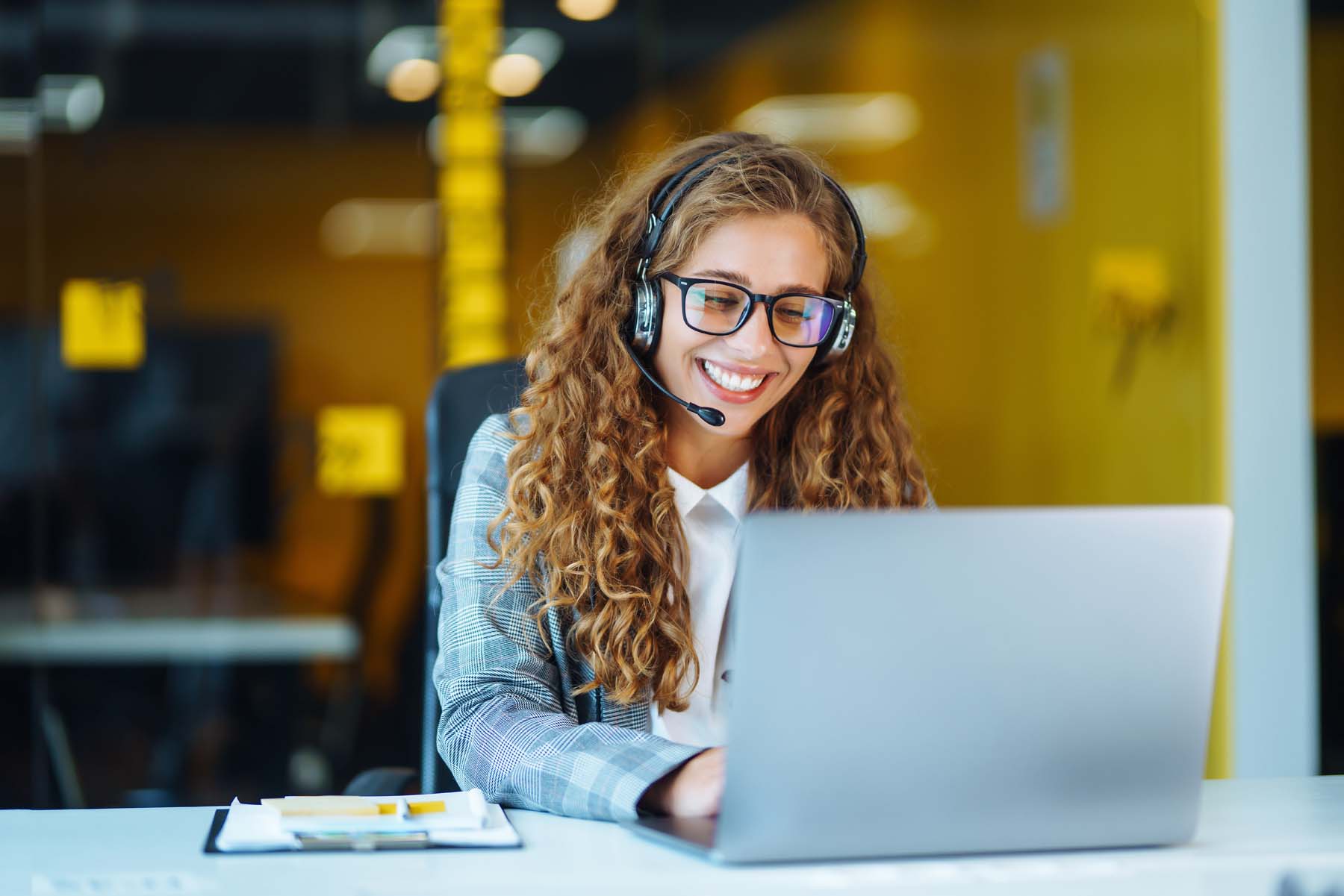 Frau mit Headset arbeitet am Laptop