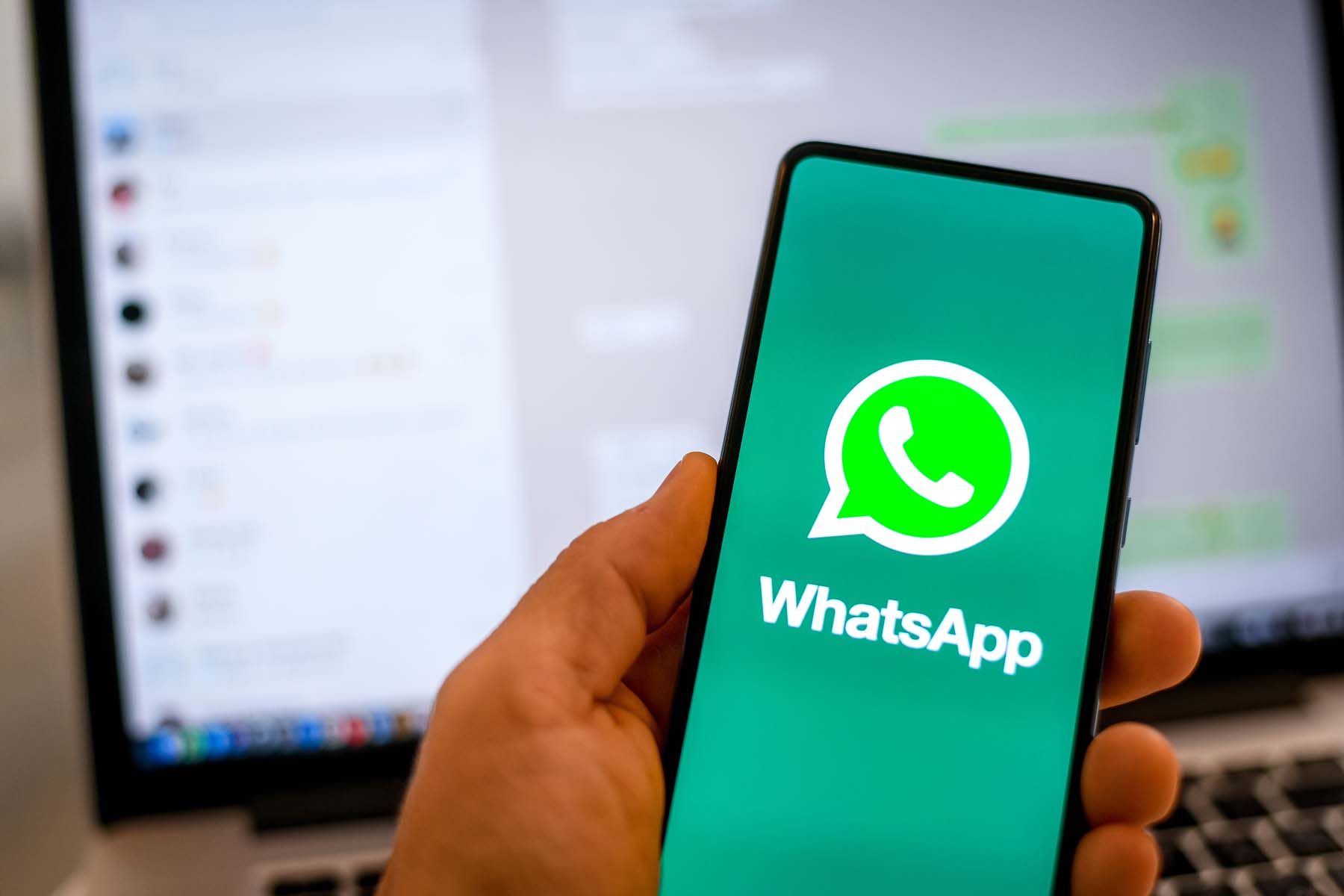 Smartphone mit WhatsApp-Logo vor einem Computerbildschirm
